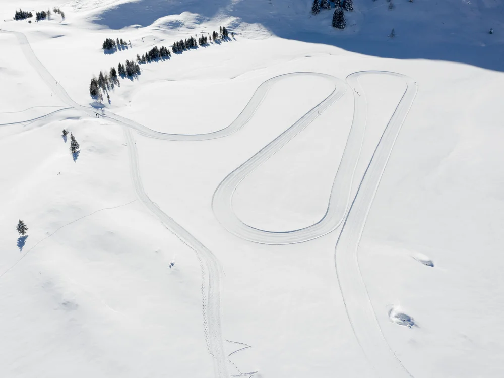 GRETI in Bad Hofgastein: dein alpines Boutique Hotel Luftaufnahme einer verschneiten Landschaft mit gewundenen präparierten Loipen und Nadelbäumen