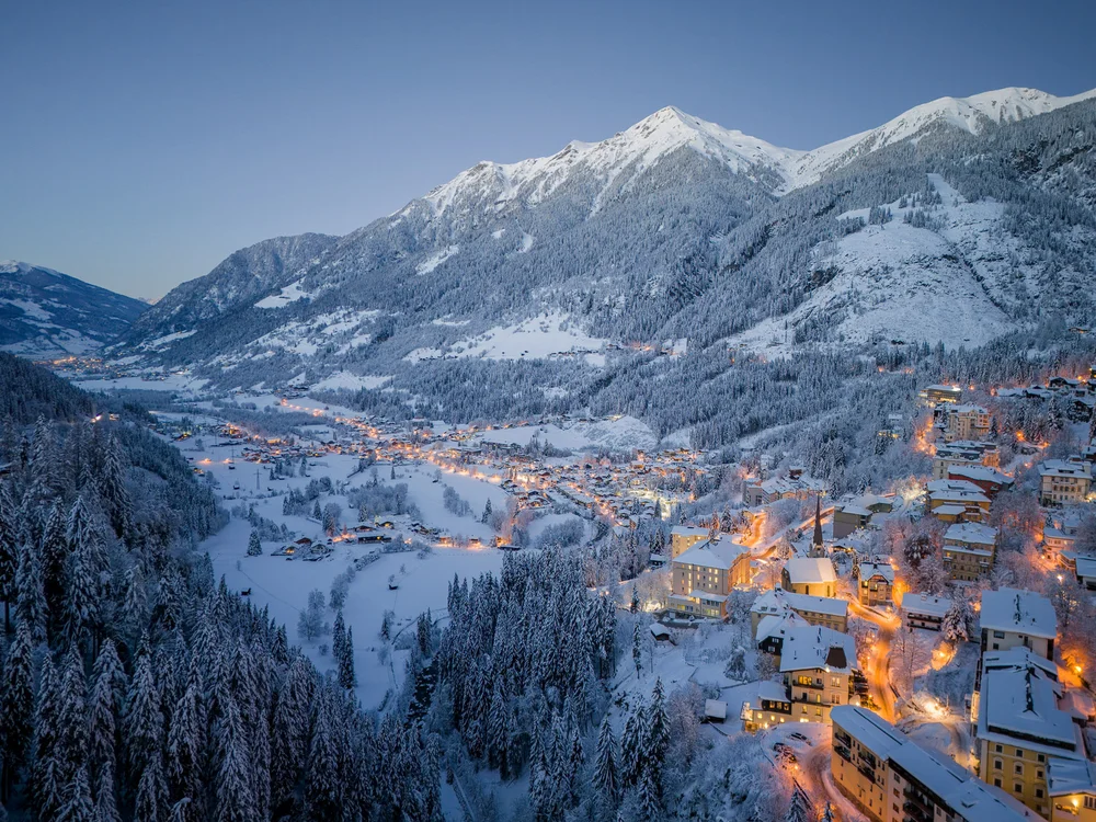 GRETI in Bad Hofgastein: dein alpines Boutique Hotel Verschneites Bergdorf im Tal mit beleuchteten Häusern und bewaldeten Bergen