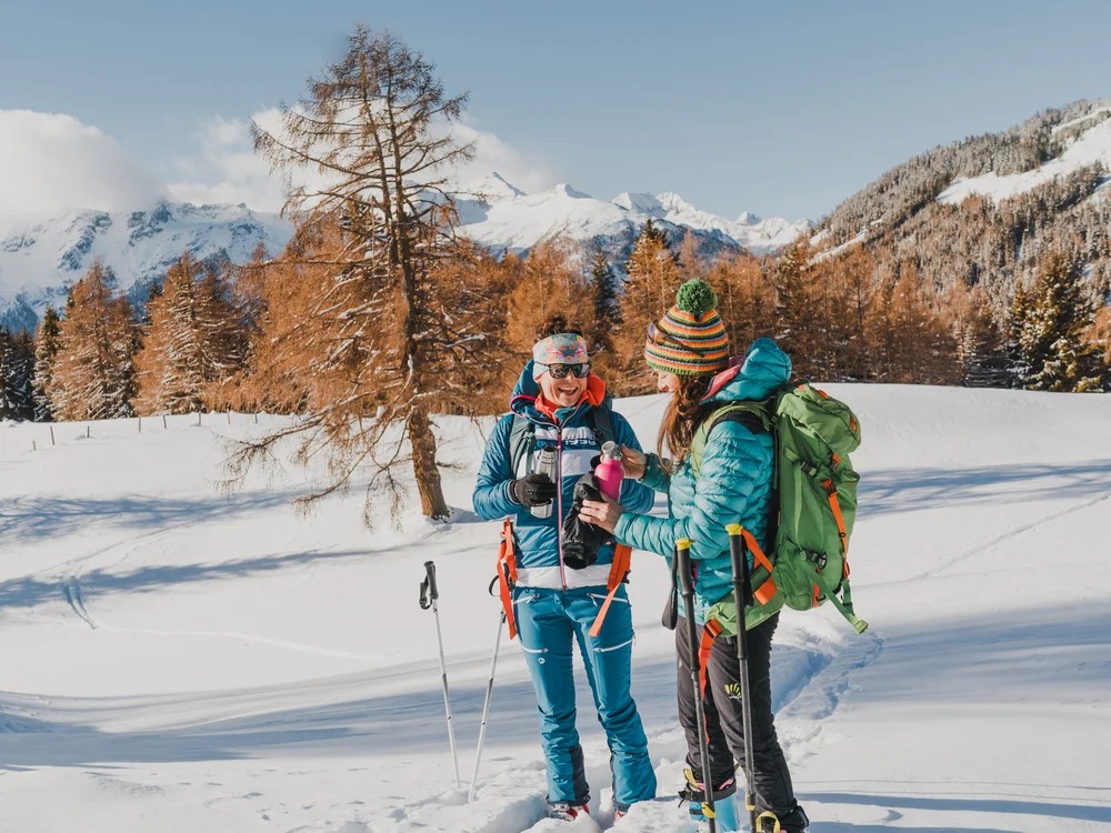 GRETI in Bad Hofgastein: dein alpines Boutique Hotel Zwei Wanderinnen in Winterkleidung trinken Tee in einer verschneiten Berglandschaft
